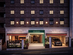 Un hotel a più piani con ingresso verde, un ristorante e un bar con musica.