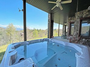 Ein Whirlpool mit Steinverkleidung, ein Deckenventilator und Blick auf eine Berglandschaft.