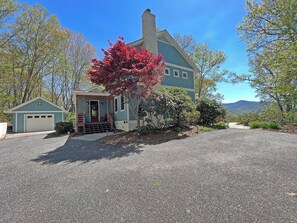 A two-story house with a garage, a porch, and a red flowering tree. - Haven in the Woods- Luxury Rental in the Heart of Bryson City, NC (Bryson City)