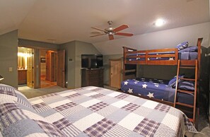 A bedroom with bunk beds, a ceiling fan, a television, and a door leading to another room. - Haven in the Woods- Luxury Rental in the Heart of Bryson City, NC (Bryson City)