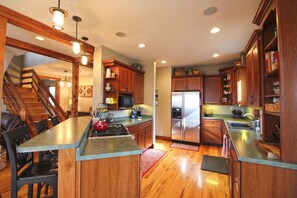 A kitchen with wooden cabinets, a stainless steel refrigerator, a microwave, and a gas stove. - Haven in the Woods- Luxury Rental in the Heart of Bryson City, NC (Bryson City)