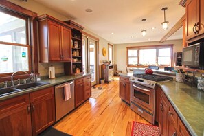 A kitchen with wooden cabinets, a stainless steel sink, a stove, and a microwave. - Haven in the Woods- Luxury Rental in the Heart of Bryson City, NC (Bryson City)