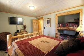 Ein Zimmer mit einem Bett, einer Bank, einem Fernseher und einem Stockbett.