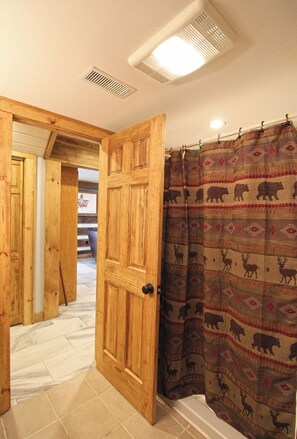 A wooden door leading to a bathroom with a shower curtain featuring animal patterns. - The Lodge at Stone Pile Gap (Bryson City)