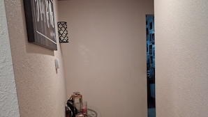 A hallway with a glass table, a framed sign, and a patterned wall decoration.