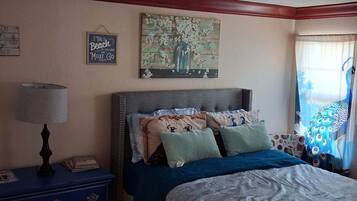 A bedroom with a bed, a nightstand, a lamp, and wall art.