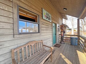 A wooden building with a porch, a bench, a sign for 'The Village Pub,' and a statue. - On Top of the World- Amazing Views (Bryson City)