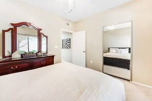 A bedroom with a large bed, a dresser, a mirror, a wardrobe, and a door leading to another room. - Prime location deluxe condo with pool and hot tub in beautiful Phoenix (Phoenix)