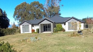 Une maison de plain-pied avec un porche à l’avant, un garage et un petit jardin à l’arrière.