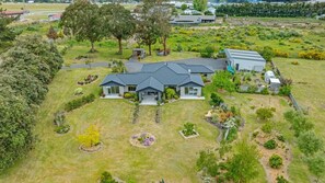Uma casa grande e moderna, com um gramado e jardim espaçosos, rodeada por árvores e vegetação.