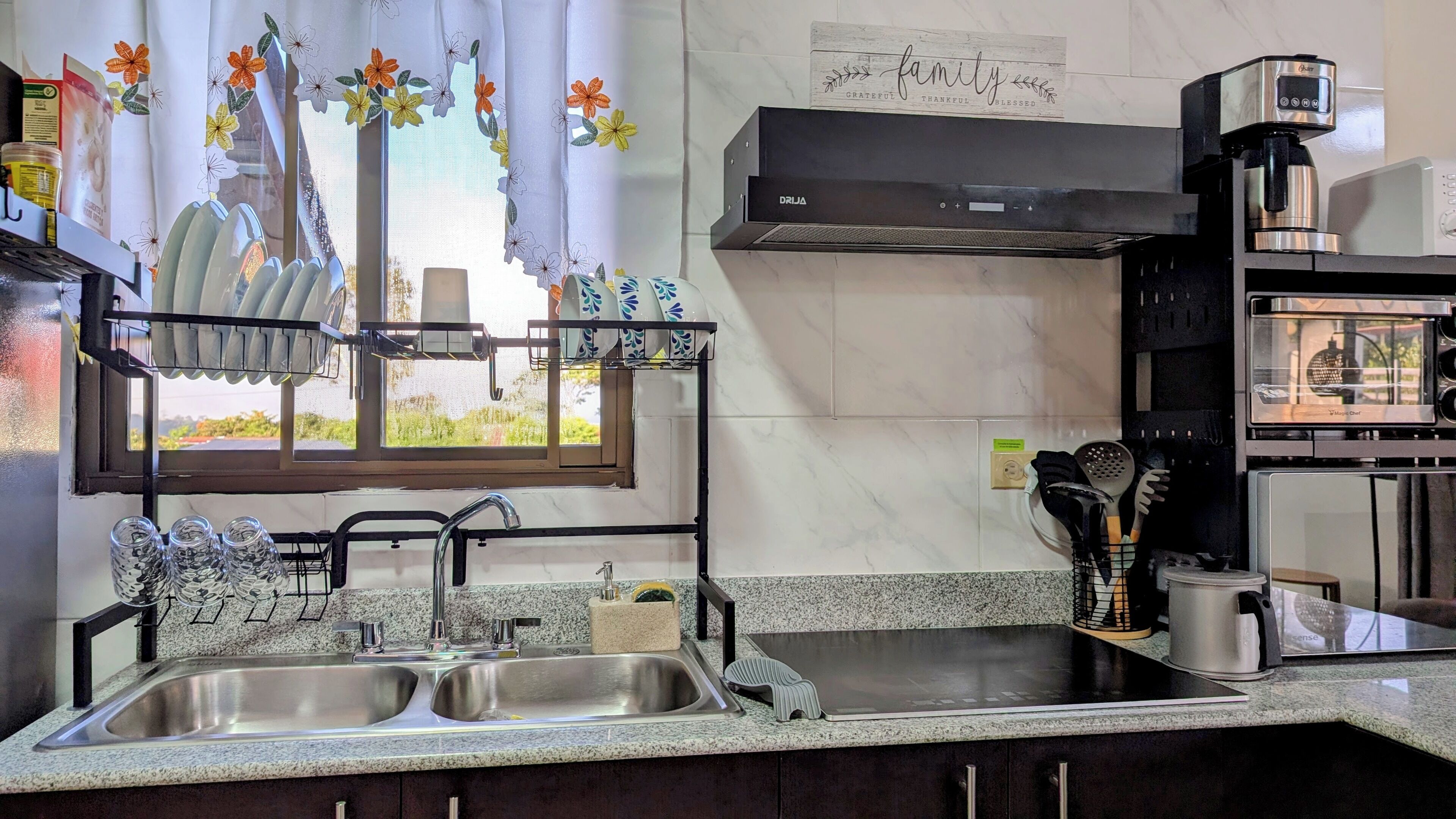 Een keuken met een dubbele spoelbak, een koffiezetapparaat en een magnetron.