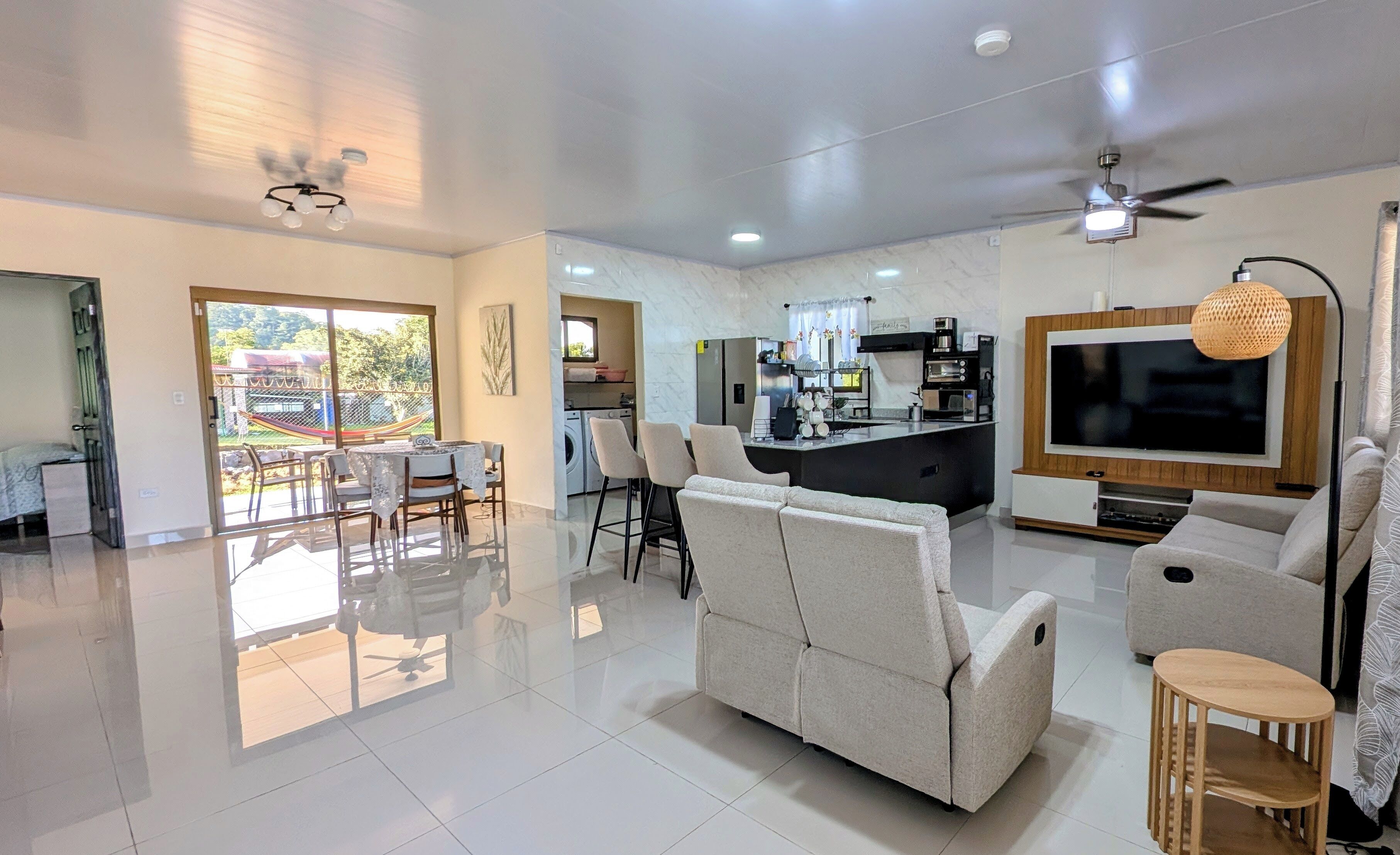 A modern living room with a sofa, TV, and a dining area with chairs and a table.