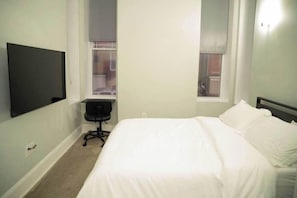 A bedroom with a bed, a desk, and a TV. - Central Station North Mega Apartment - Free (Baltimore)