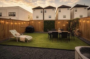 A backyard with a lawn, a dining table with chairs, a grill, and a bicycle. - Midtown Home – Free Parking, W/D, Private Yard (Houston)
