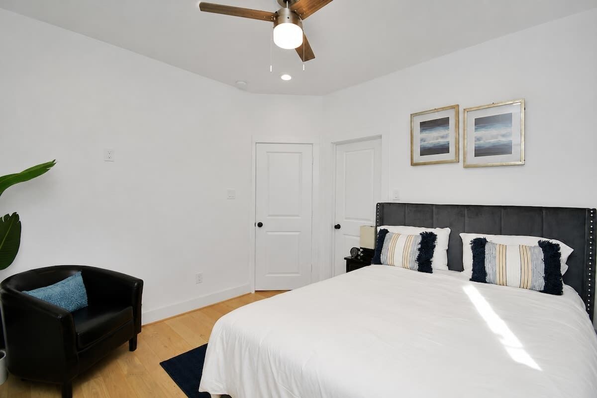Une chambre à coucher avec un lit, un ventilateur de plafond, une table de chevet et une chaise.