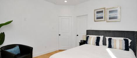 Une chambre à coucher avec un lit, un ventilateur de plafond, une table de chevet et une chaise.