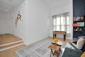 A living room with a sofa, a coffee table, a rug, and a window with curtains. - Midtown Home – Free Parking, W/D, Private Yard (Houston)