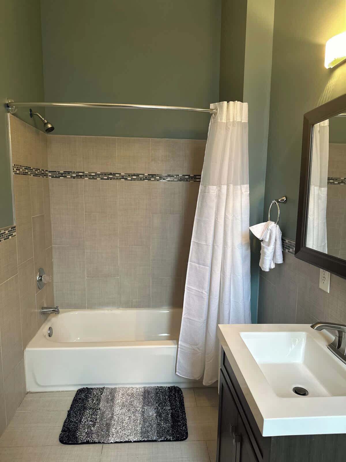 A bathroom with a bathtub, a sink, a mirror, and a shower curtain.