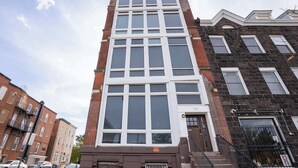 A multi-story building with a central entrance, a fire escape on the right, and a visible address number. - Spacious PennStation Downtown Penthouse W/ Parking (Baltimore)