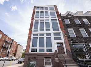 A multi-story building with a central entrance, a fire escape on the right, and a visible address number. - Spacious PennStation Downtown Penthouse W/ Parking (Baltimore)
