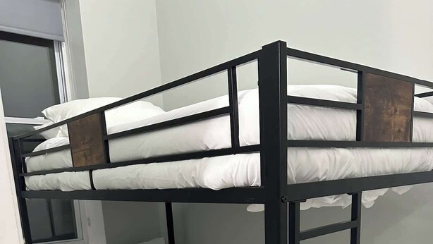 A bunk bed with white bedding in a room with a carpeted floor and a window. - Spacious PennStation Downtown Penthouse W/ Parking (Baltimore)