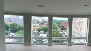 A room with large windows offering a view of a cityscape. - Spacious PennStation Downtown Penthouse W/ Parking (Baltimore)