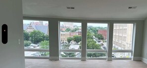 A room with large windows offering a view of a cityscape. - Spacious PennStation Downtown Penthouse W/ Parking (Baltimore)