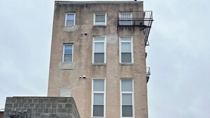 A multi-story building with a brick facade, several windows, and a visible entrance. - Massive Downtown Penn Station apt with parking (Baltimore)