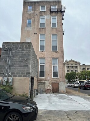 A multi-story building with a brick facade, several windows, and a visible entrance. - Massive Downtown Penn Station apt with parking (Baltimore)