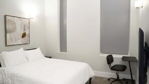 Ein Hotelzimmer mit Bett, Sessel, Schreibtisch und großem Fenster.