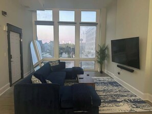 A living room with a large window, a sofa set, a flat-screen TV, and a potted plant. - Very large! Penn Station Downtown home w/parking (Baltimore)