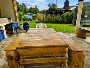Une table en bois avec des bancs, dans un espace extérieur abrité.