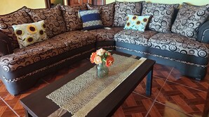 A sectional sofa with patterned cushions, a woven placemat, and a vase with flowers on a coffee table.