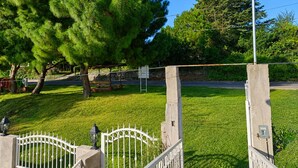 A grassy area with a metal gate, a bench, and a lamppost.