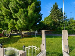A grassy area with a metal gate, a bench, and a lamppost.