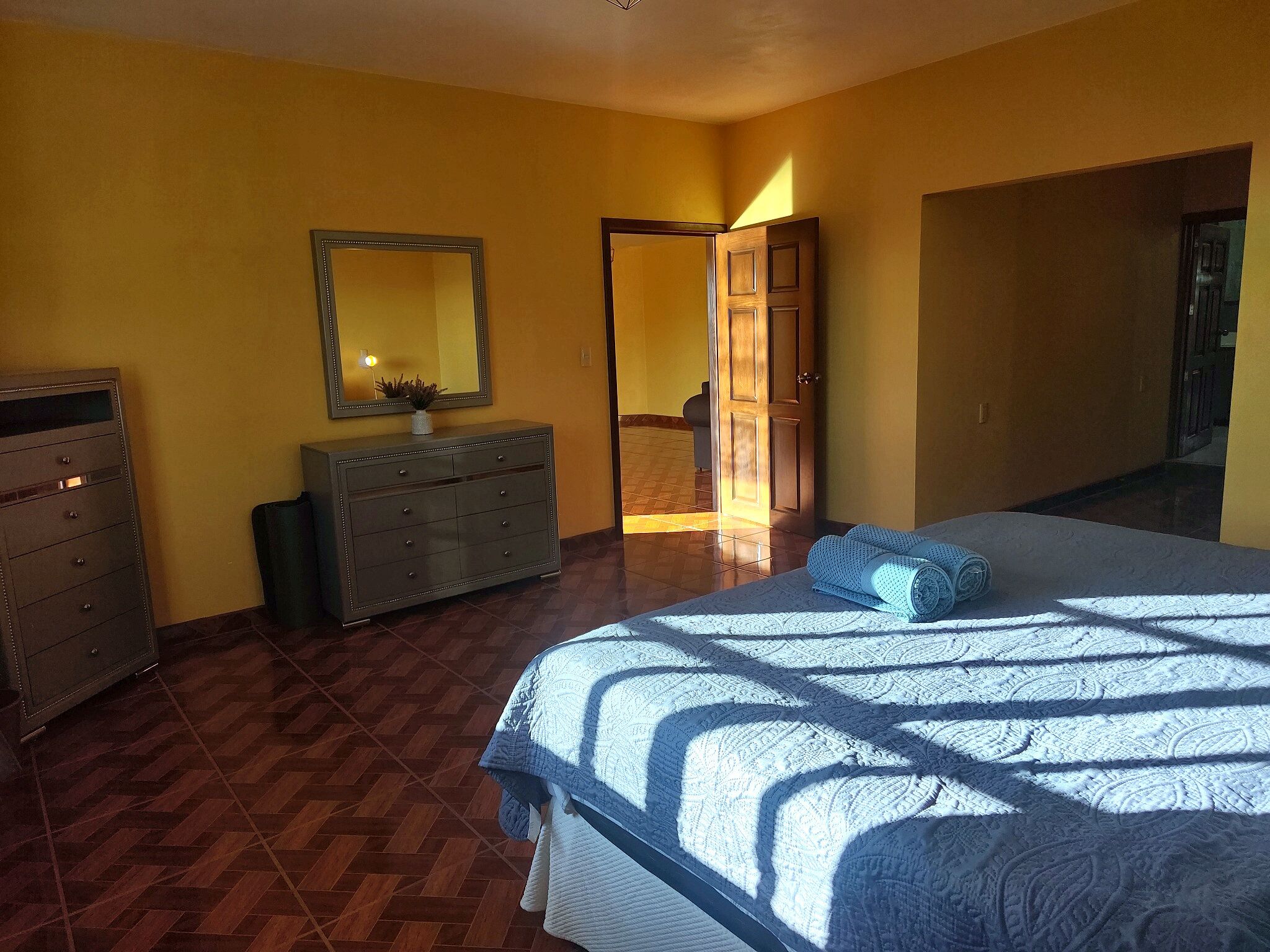 A bedroom with a bed, dresser, and a mirror.