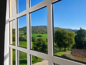 A view through a window with a clear sky and a green landscape with hills.