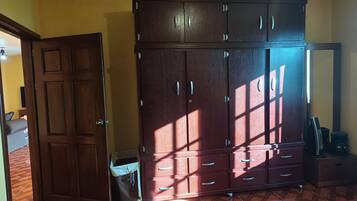 Una habitación con un armario de madera grande, una cama con cubre cama azul y suelo de baldosas.