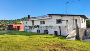 A two-story house with a white exterior, a red building adjacent to it, and a grassy yard.