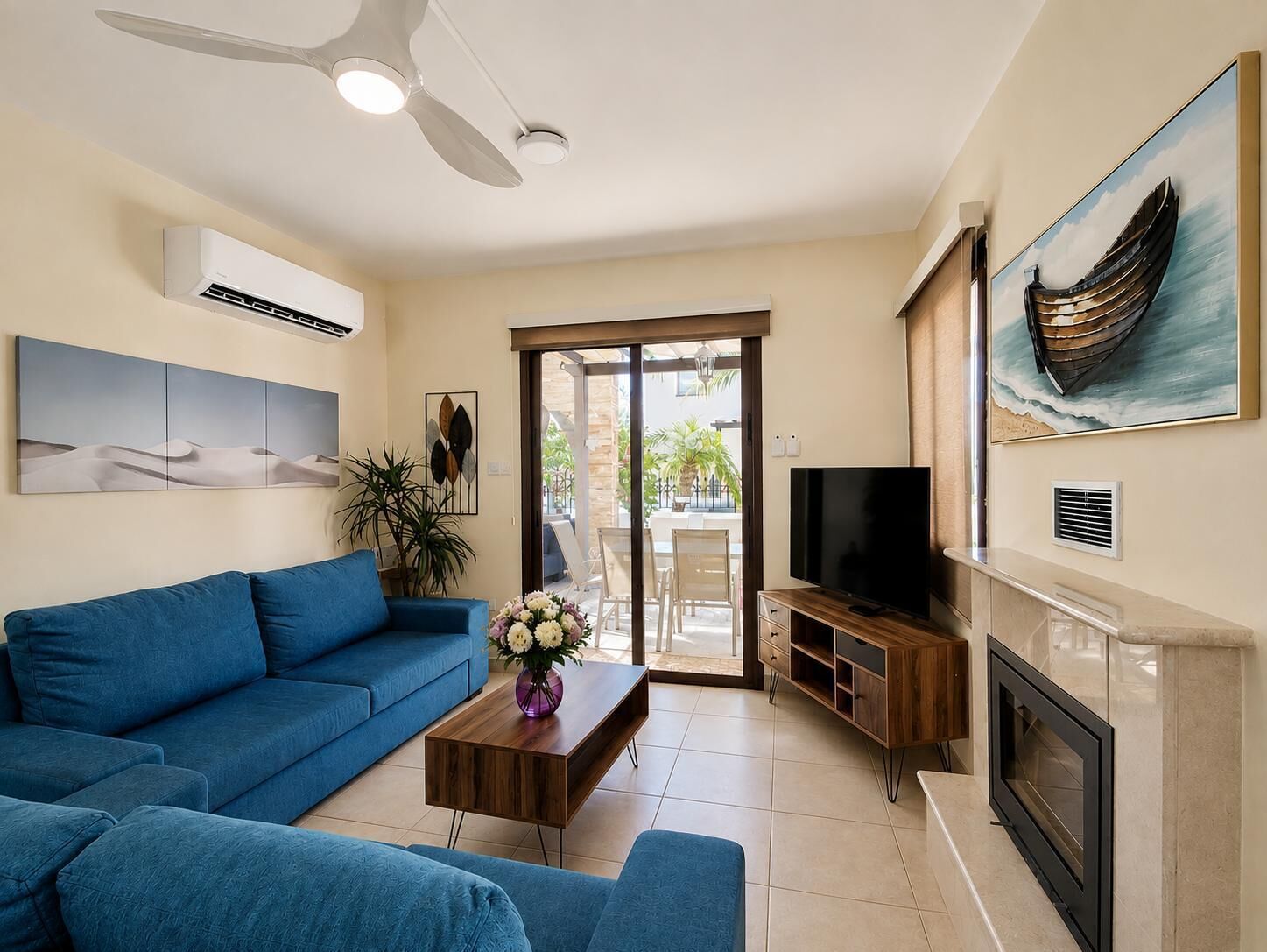 A living room with a blue sofa, a wooden coffee table, a flat-screen TV, and a fireplace.