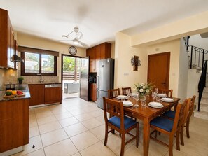 Une cuisine moderne avec des meubles en bois, un four encastré et un coin repas comprenant une table et des chaises en bois.