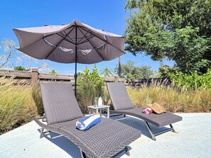 Dues cadires de relaxació amb un parasol gran, una taula petita i una ampolla d'aigua.