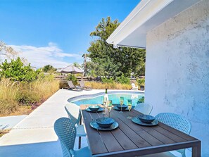 A poolside dining area with a table set for four, surrounded by chairs.