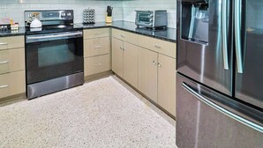 Une cuisine moderne dotée d’appareils électroménagers en acier inoxydable, de meubles de couleur claire et d’un plan de travail en granit.