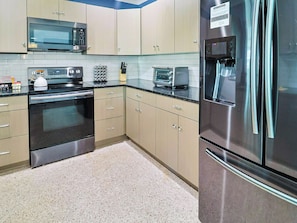 A modern kitchen with stainless steel appliances, light-colored cabinets, and a granite countertop. - Siesta Key 3BR w/ Heated Pool, Game Room & Lanai (Sarasota)