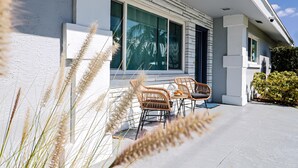 Une maison moderne dotée d’un patio, de deux fauteuils en osier et d’une table.