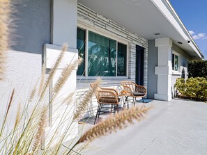 A modern house with a patio, two wicker chairs, and a table. - Siesta Key 3BR w/ Heated Pool, Game Room & Lanai (Sarasota)
