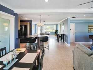 A modern kitchen with a central island, dining area with a table and chairs, and a living room with a sofa. - Siesta Key 3BR w/ Heated Pool, Game Room & Lanai (Sarasota)