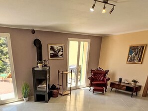 Ein geräumiges Wohnzimmer mit Kamin, einem roten Sessel und einem Essbereich mit Tisch und Stühlen.