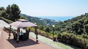 Una terraza con mobiliario exterior, vistas al mar y un jardín ajardinado.